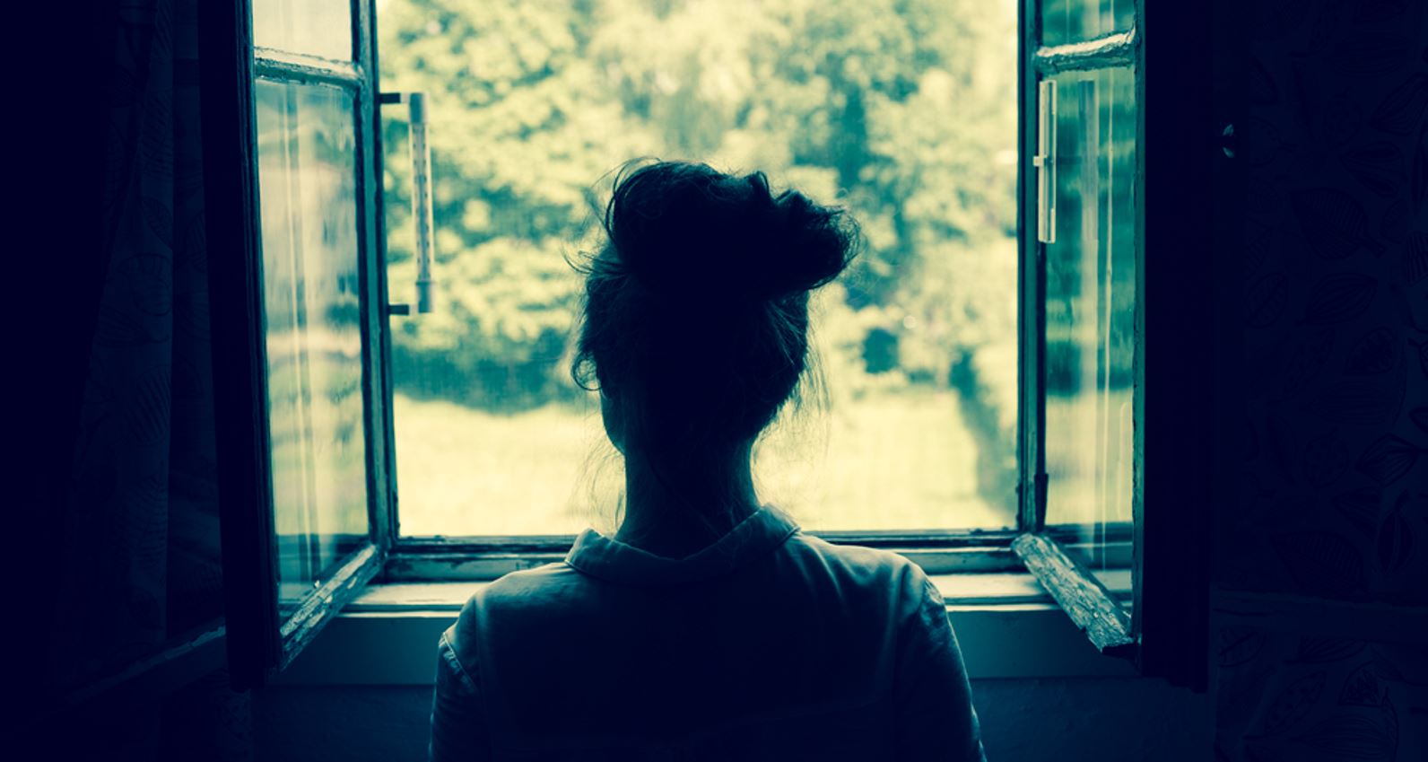 Silhouette of a woman looking out of a window