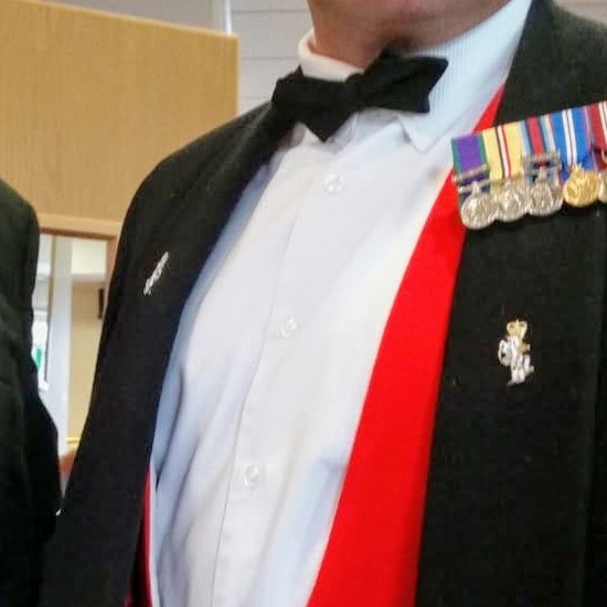 an image of a man in smart dress showing war medals
